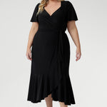 Luxe Alita Wrap Dress in Black with soft sheen fabric, flattering ruching, and deep ruffle hem for an elevated evening look.