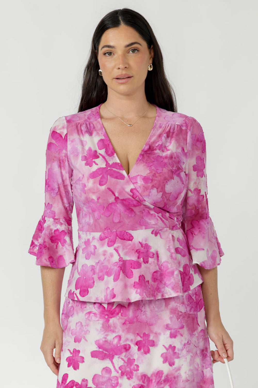 Amora Top crafted from luxe textured burnout fabric with soft stretch, featuring a feminine wrap silhouette, defined waist and flowing peplum hem.