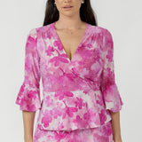 Amora Top crafted from luxe textured burnout fabric with soft stretch, featuring a feminine wrap silhouette, defined waist and flowing peplum hem.