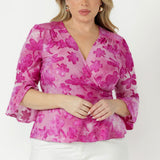 Women’s Amora wrap top in surface-textured burnout fabric with wrap-around waist ties, fluted 3/4 sleeves and an elegant peplum silhouette.