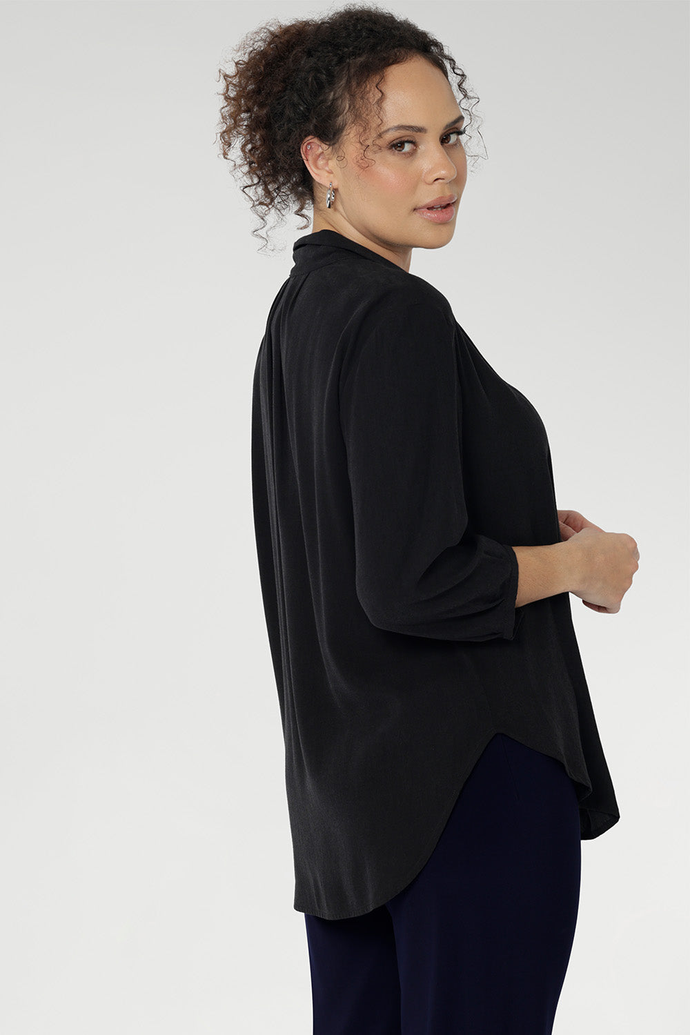 Side view of woman wearing Graphite coloured woven shirt with collar and tailored pleat with navy workwear pants. Made from sustainable Tencel fabric in Australia in sizes 8-24. 