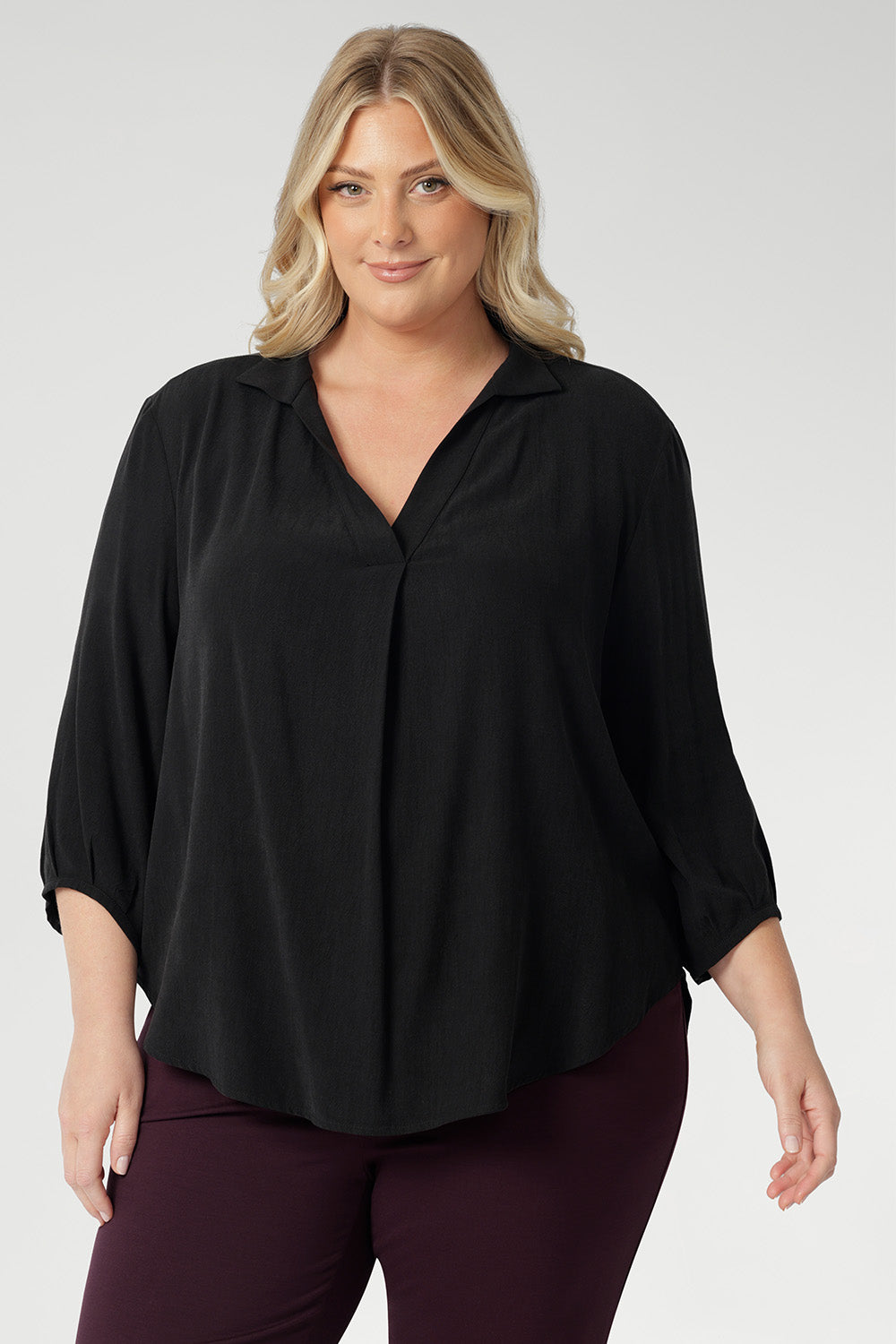 Plus size woman wearing woven shirt with collar and tailored pleat with wine coloured workwear pants. Made from sustainable Tencel fabric in Australia in sizes 8-24. 