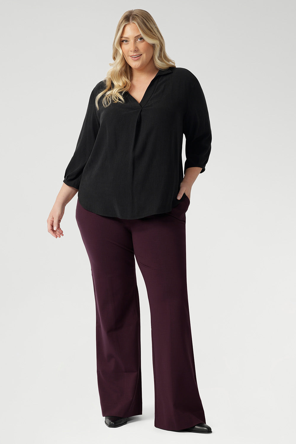 Plus size woman wears Graphite coloured woven shirt with collar and tailored pleat with wine work pants and black boots. Made from sustainable Tencel fabric in Australia for petite and plus size woman sizes 8-24. 