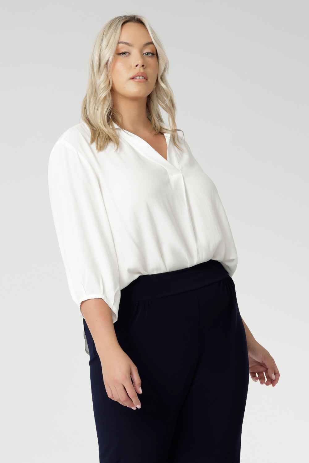 Plus size woman wears Vanilla workwear shirt. A soft tailored shirt with 3/4 sleeves, collar neckline and shirttail hem. Pull on style shirt is made in Australia from sustainable Tencel fabric. Easy care workwear blouse for women, available in 8-24.