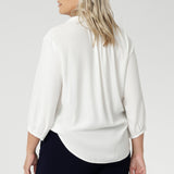 Back view image of size 18 woman wearing the Arley Shirt in in Vanilla. A soft tailored shirt with 3/4 sleeves, collar neckline and shirttail hem. Pull on shirt is made in Australia of sustainable tencel fabric. Soft and easy care workwear for women for petite to plus size 8-24. Styled back with a Bradley culotte in navy. 