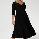 Size 18 woman wears a black reversible Bettina dress in black Jersey dress made in Australia. V-neck style with pockets and midi length. Made in Australia for women size 8 - 24. Reversible dress can be worn featuring boat neck or neck.