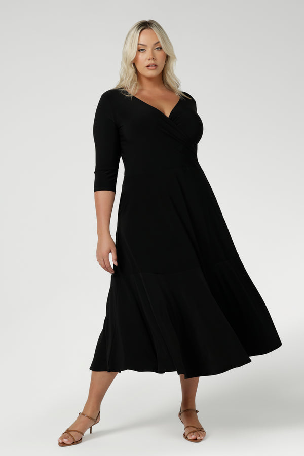 Size 18 woman wears a black reversible Bettina dress in black Jersey dress made in Australia. V-neck style with pockets and midi length. Made in Australia for women size 8 - 24. Reversible dress can be worn featuring boat neck or neck.