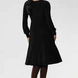 Featuring a sophisticated V-neckline with a twist-front bodice and cuffed long sleeves, it creates a flattering silhouette with elegant detail.