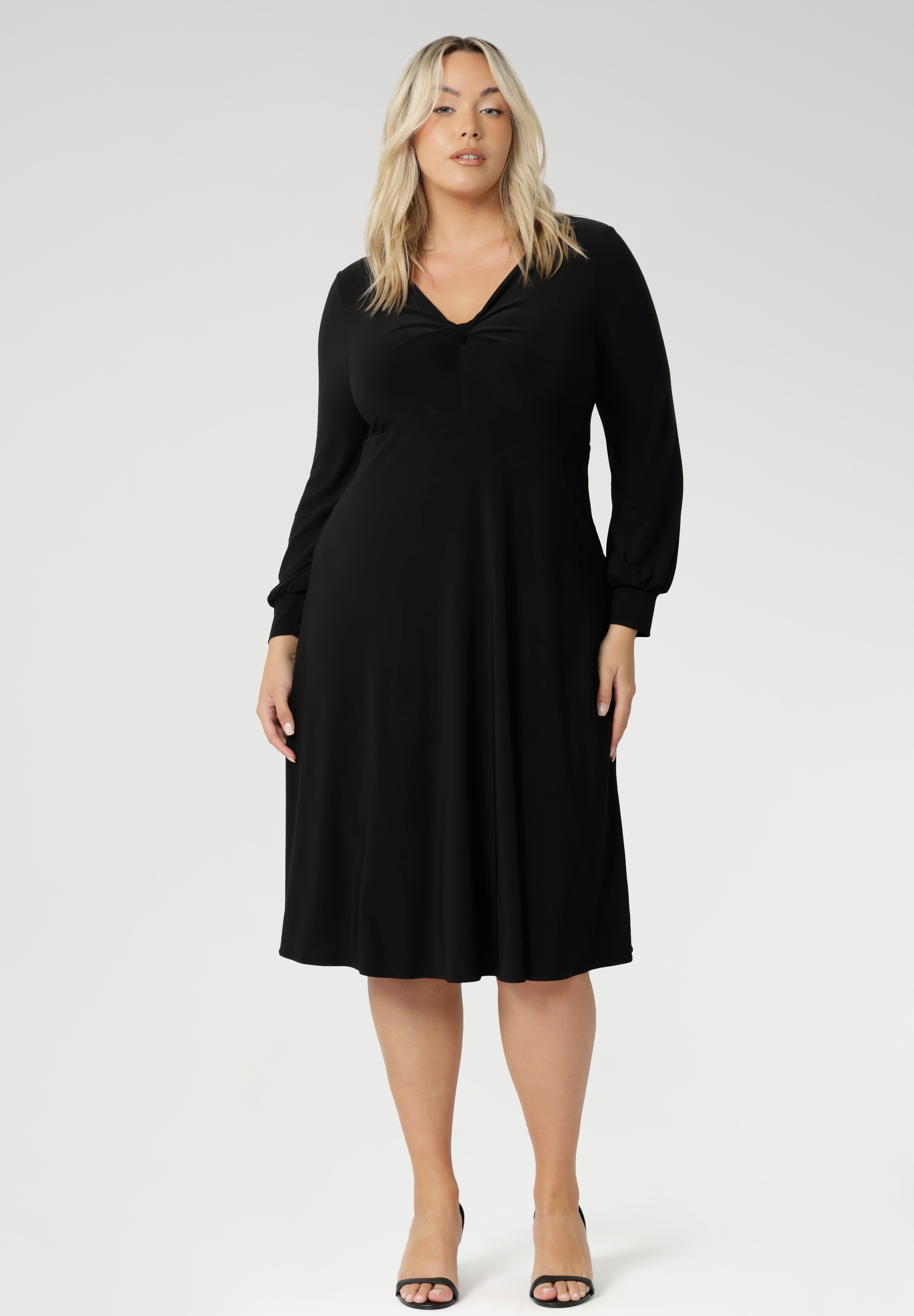 The Bianca Dress is a versatile wardrobe essential, designed to take you from work to events with effortless elegance. This classic black knee-length dress features a flattering V-neckline and a twist-front bodice that enhances your shape, while the cuffed long sleeves add a polished finish.