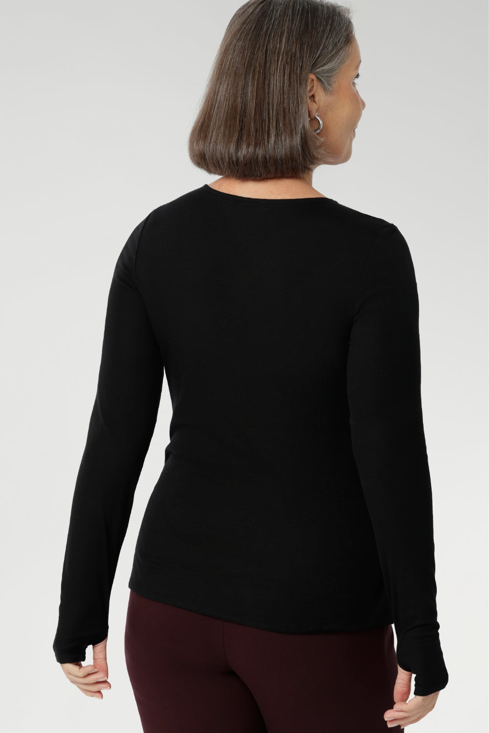 Stay effortlessly stylish through the cooler months with this luxuriously soft knit top, crafted from a premium Tencel wool blend. Designed for comfort and versatility, it features a flattering close-to-body fit that moves with you, thanks to its generous stretch and breathable finish. Black knit top has thumbholes that can be used or tucked away for versatility in styling and extra warmth. 