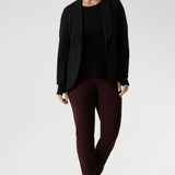 Size 10 woman wears knit top under black work wear blazer. Designed for comfort and versatility, it features a flattering close-to-body fit that moves with you, thanks to its generous stretch and breathable finish. Black knit top has thumbholes that can be used or tucked away for versatility in styling and extra warmth. Available in size 8-24.