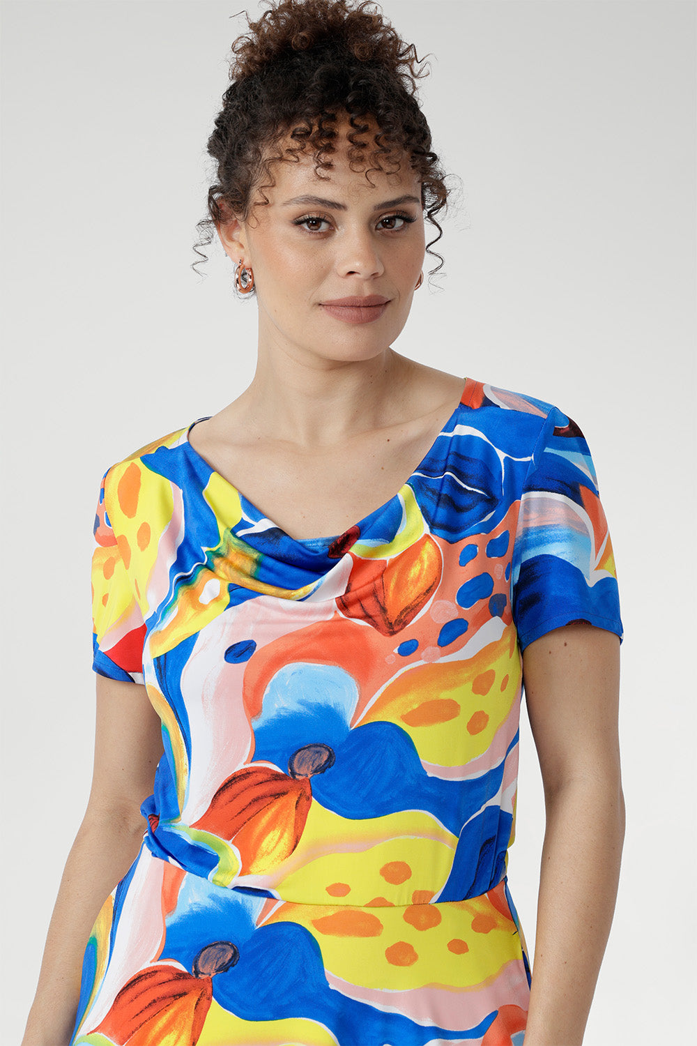 With its cowl neckline, relaxed blouson shape, and flowing asymmetrical skirt, this floral beauty is perfect for sunny days, seaside escapes, and easy weekends. Made in Australia, sizes 8–24.