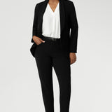 Image of a 40-year-old woman wearing work wear pants in Black Scuba Crepe. This easy care pant is made of scuba crepe fabric and gives a luxe stretch feel. Comfortable off duty pants are made in Australia for women sized 8-24. Pants are photographed with matching black blazer for a full suit look.