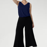 A size 10 woman wears black wide-leg pants and navy top. Cropped in length, the black pants have a smooth waistband, side pockets and are pull-on pants made in stretch jersey. Made in Australia, the pants are size inclusive in sizes 8 - 24.