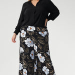Plus size woman wears the Ellis shirt in Graphite Black styled tucked into printed wide leg pants and black heels for an elevated stylish. 