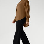 The full-length sleeves are finished with clean cuffs and covered buttons — an understated touch that elevates the look. A gently curved shirttail hem sits longer at the back, offering balanced proportions and flattering coverage.