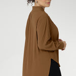 Plus size woman wears lightweight, easy to wear shirt that holds its shape without stretch. In the warm neutral shade of Nuthatch, it brings subtle sophistication to everyday dressing. The full-length sleeves are finished with clean cuffs and covered buttons — an understated touch that elevates the look. A gently curved shirttail hem sits longer at the back, offering balanced proportions and flattering coverage. Available in size 8-24.