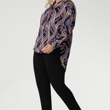 The Ellis Shirt is a versatile, statement-making piece perfect for work, weekends, or layering under jackets throughout the season. Plus size model wears geometric shirt with black work pants. 