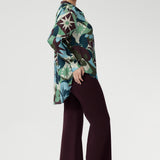 Designed with a flattering oversized silhouette, this effortless pull-on shirt drapes beautifully whether worn loose or stylishly front-tucked. The bold abstract print blends rich tones of green, blue, and plum, making it a standout for both professional and social settings.