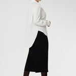 Back view of a size 10 woman wears the Ellis shirt in Vanilla tencel, a high quality made in Australia womens shirt made in breathable tencel. Inclusive size range 8-24 and made in Australia. Styled with black midi tube skirt and brown boots. 