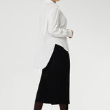 Back view of a size 10 woman wears the Ellis shirt in Vanilla tencel, a high quality made in Australia womens shirt made in breathable tencel. Inclusive size range 8-24 and made in Australia. Styled with black midi tube skirt and brown boots. 