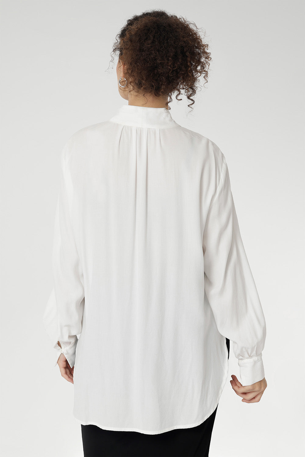 Back view of a size 10 woman wears the Ellis shirt in Vanilla tencel, a high quality made in Australia womens shirt made in breathable tencel. Inclusive size range 8-24 and made in Australia. Styled back with the Deni pants in Black velour.