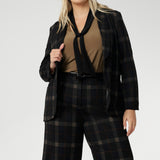Designed for women who want style that works across occasions, this jersey top blends comfort with quiet sophistication. The soft V-neckline is accented by attached neck ties in a warm coffee tone, offering styling versatility. Plus zie woman wears her neck tie top under plaid suit set with matching blazer and wide leg pants.