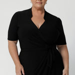 A size 18 woman wears the Kris dress in black. A functioning wrap work dress in soft black jersey. Great for being comfortable in the office. Made in Australia for women size inclusive fashion 8 - 24.