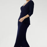 Whether you're in the office or heading to after-work events, the Kyle Top delivers confidence and style with ease. Size 10 model wears navy wrap top with navy midi  skirt and black boots for a faux dress look.