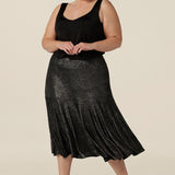 A size 18, plus size woman wears a midi length, foil print evening skirt with ruffle hem. For cocktail and evening wear, this elegant skirt is worn with a black cami top. Both going out skirt and top are made in Australia by women's fashion brand, Leina & Fleur. Shop their evening and cocktail wear online in sizes 8 to 24.