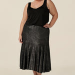 A size 18, plus size woman wears a midi length, foil print evening skirt with ruffle hem. For cocktail and evening wear, this elegant skirt is worn with a black cami top. Both cocktail skirt and top are made in Australia by women's fashion brand, Leina & Fleur. Shop their evening and cocktail wear online in petite to plus sizes.
