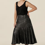 A size 10, petite height woman wears a midi length, foil print evening skirt with ruffle hem. Styled with a black cami top as a cocktail wear outfit, both are made in Australia by women's fashion brand, Leina & Fleur. Shop evening and cocktail wear online in sizes 8 to 24.