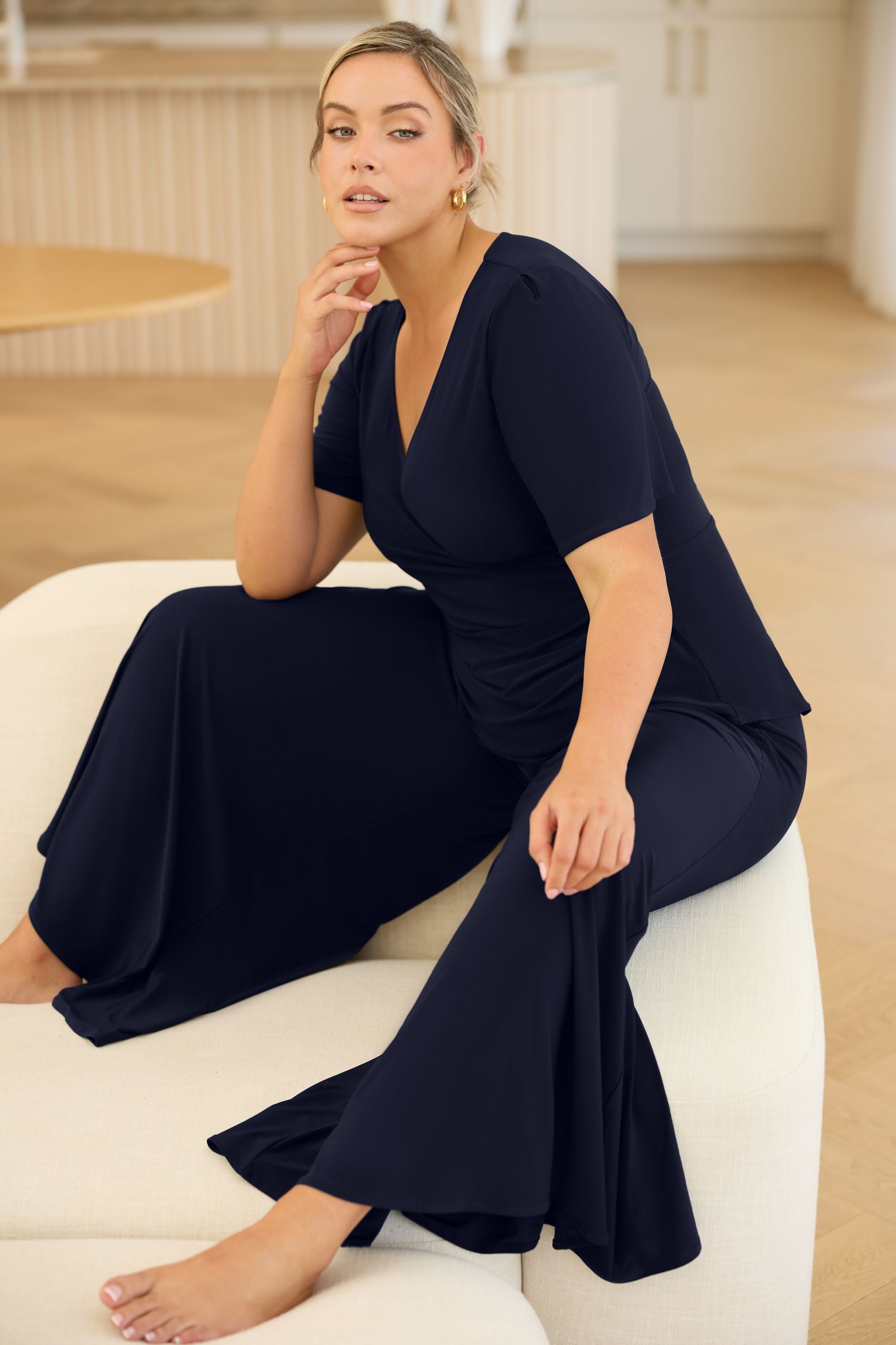 Crafted from luxe slinky fabric in a rich deep navy, the Lyle Top in Dark Navy features a flattering V-neck wrap front with a soft flounce detail. With short sleeves and a versatile silhouette, it layers effortlessly under jackets or stands alone as a polished summer essential.