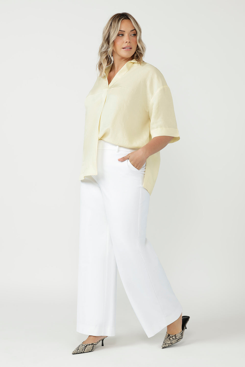 Luxe Martha Shirt featuring a relaxed oversized fit, natural textured fabrication and refined tailoring, proudly designed and made in Australia. Plus size women wears relaxed linen tee paired with white dress pants & heels