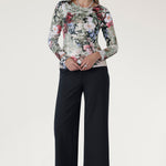 he top features a straight front hemline with a curved back hem that sits slightly longer, offering modern movement and easy styling with skirts, pants, or layering pieces.