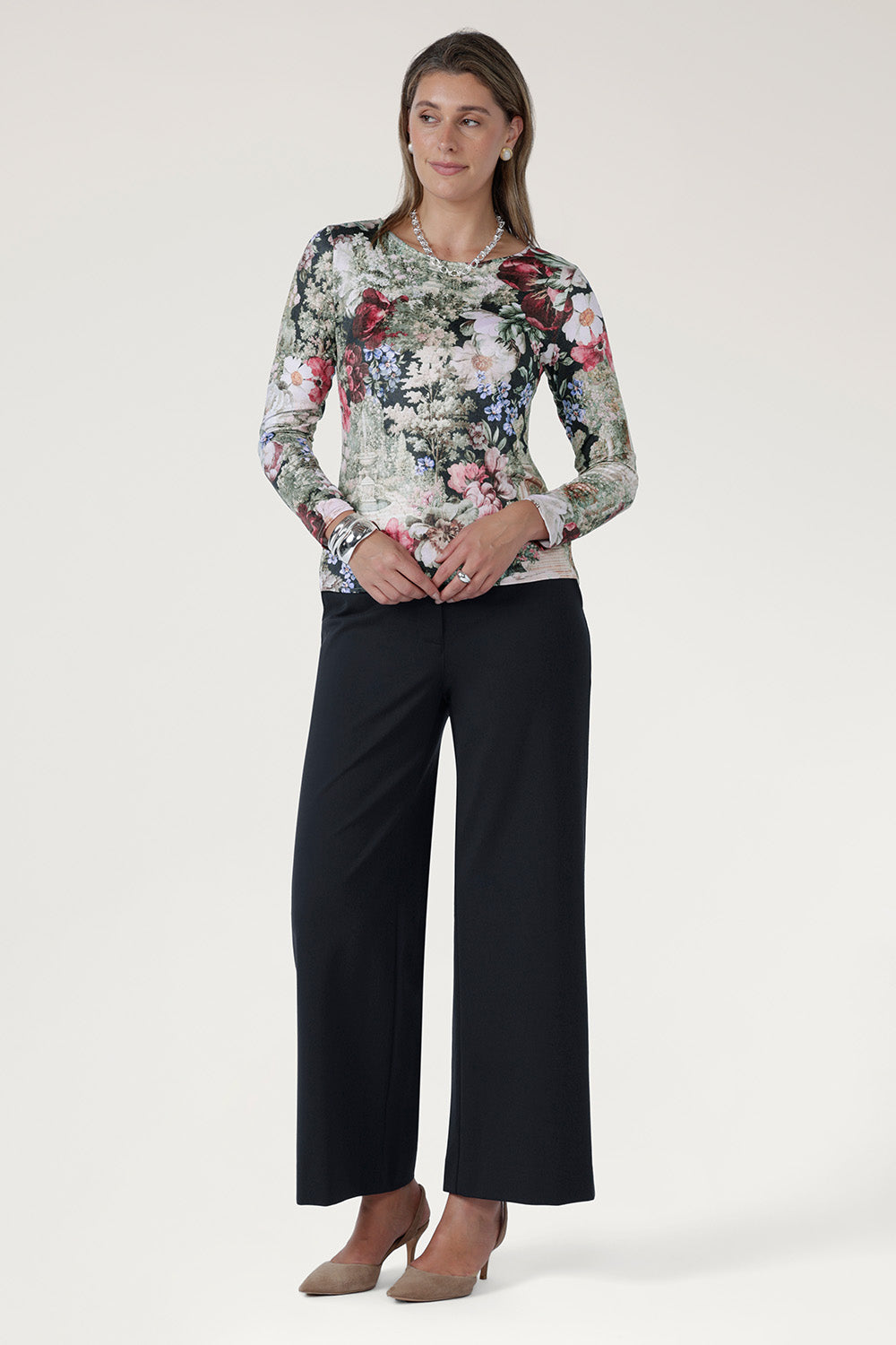 he top features a straight front hemline with a curved back hem that sits slightly longer, offering modern movement and easy styling with skirts, pants, or layering pieces.