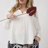 This elevated pull-on shirt features a refined collared neckline, full-length sleeves with covered-button cuffs, soft gathering through the front shoulders and back yoke, and a flattering shirttail hemline.