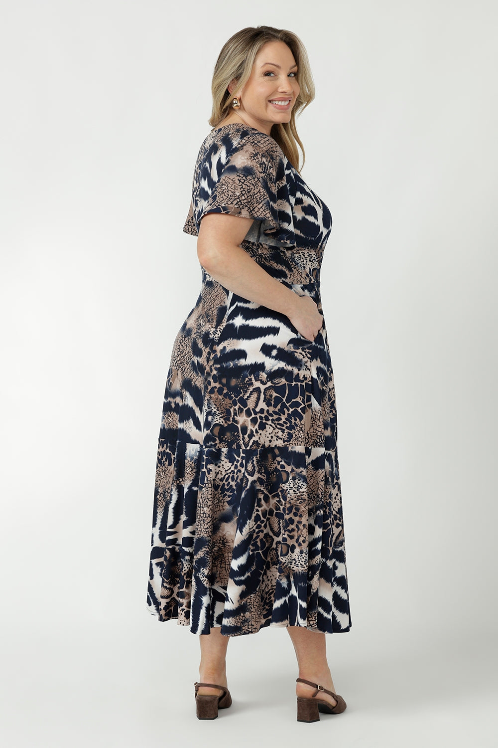 Australian-made Nicolle Dress featuring a fixed wrap bodice, elegant flutter sleeves and a flattering full skirt with ruffle hemline for effortless occasion dressing.