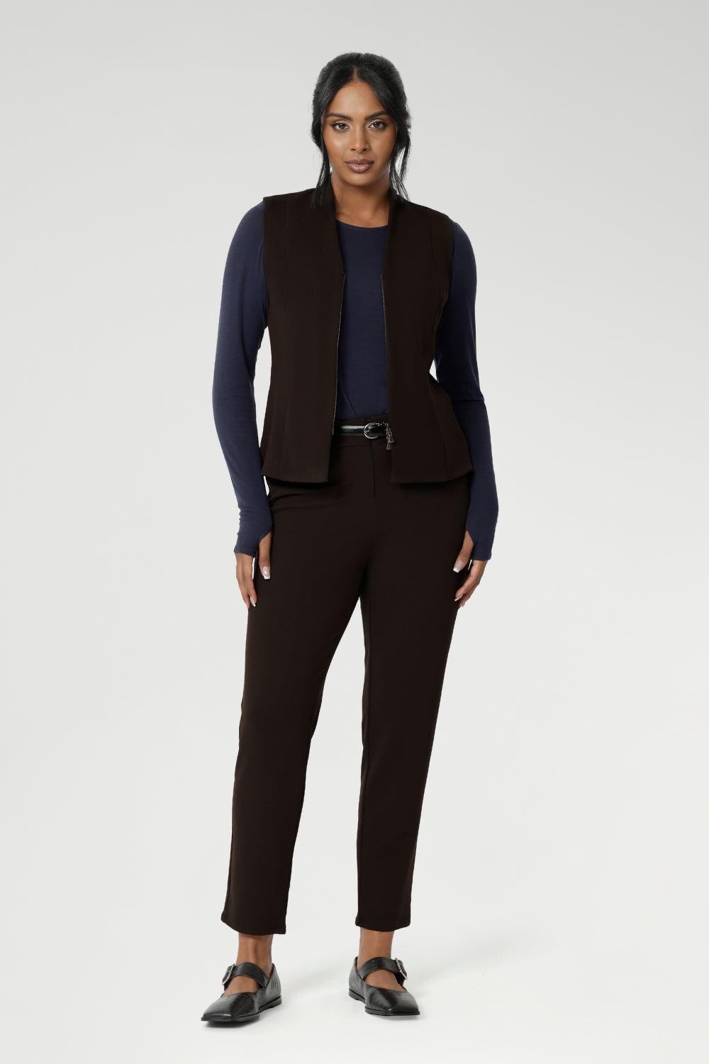 Designed for comfort and versatility, it features a flattering close-to-body fit that moves with you, thanks to its generous stretch and breathable finish. Size 10 woman wears her wool top tucked into her cocoa coloured tapered leg pants, and matching vest.