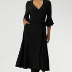 Size 10 corporate woman wears the Portia dress in Black. A wrap dress in black with tie side and 3/4 sleeve. Styled with long brown boots. Made in Australia for women size 8 - 24.