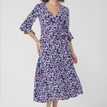 Featuring a soft wrap neckline, fluted 3/4 sleeves with gathered detail, and pockets, it’s designed with comfort, elegance and movement in mind.