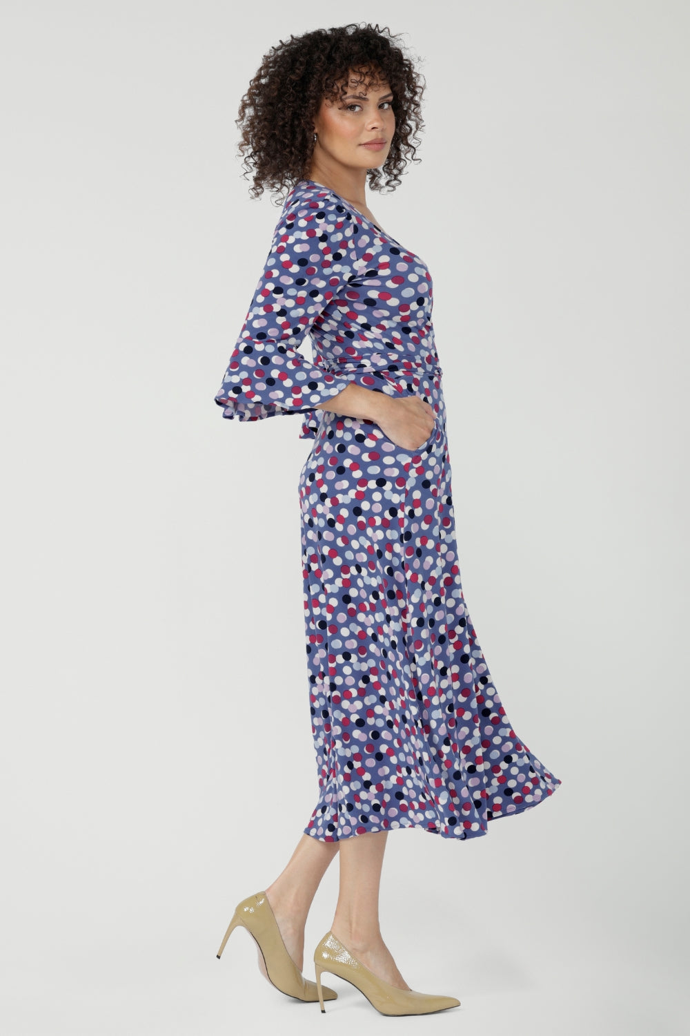 Featuring a soft wrap neckline, fluted 3/4 sleeves with gathered detail, and pockets, it’s designed with comfort, elegance and movement in mind.