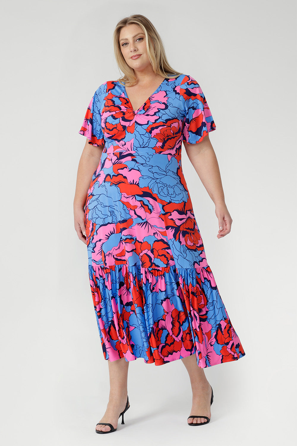 Crafted from slinky jersey, the Rio Dress in Can Can is a lightweight maxi featuring a flattering empire-line bodice, deep V-back, flared sleeves, and a gathered hem with a flowing tail effect—perfect for effortless summer elegance.