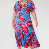 Crafted from slinky jersey, the Rio Dress in Can Can is a lightweight maxi featuring a flattering empire-line bodice, deep V-back, flared sleeves, and a gathered hem with a flowing tail effect—perfect for effortless summer elegance.