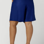 Back view of a size 16 woman wears Cobalt Linen Bermuda short in Cobalt. High waist short with pleat front and self cover buttons. Bermuda short length. Made in Australia for women size 8 - 24.