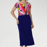 The Tucan print blends abstract strokes of pinks, reds, greens, and black on a warm cream base, creating a vibrant, artful pop that enlivens any outfit. Size 10 woman wears her Sawyer top with a cobalt colour skirt to make the print pop.