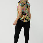 Back view of a size 10 woman wears the Sawyer Top in jersey with Zanzibar print. A multi coloured print with a black base and beautiful bright colours. Made in Australia for women size 8-24. Styled back with the Indi Pant in Black.  
