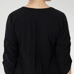 The back neckline is finished with a facing and a soft pleat that adds subtle detail. The 3/4 length sleeves include elegant ruching that falls toward the centre front of the arm for a refined finish.