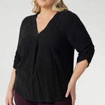 Plus size woman wears 3/4 length sleeve top with elegant ruching details that falls toward the centre front of the arm for a refined finish. She's styled her Terry Shirt in Graphite with wine coloured pants. 