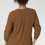 The back is finished with a subtle pleat for a touch of structure and flow. With beautifully ruched ¾ sleeves that fall gracefully toward the front of the arm.